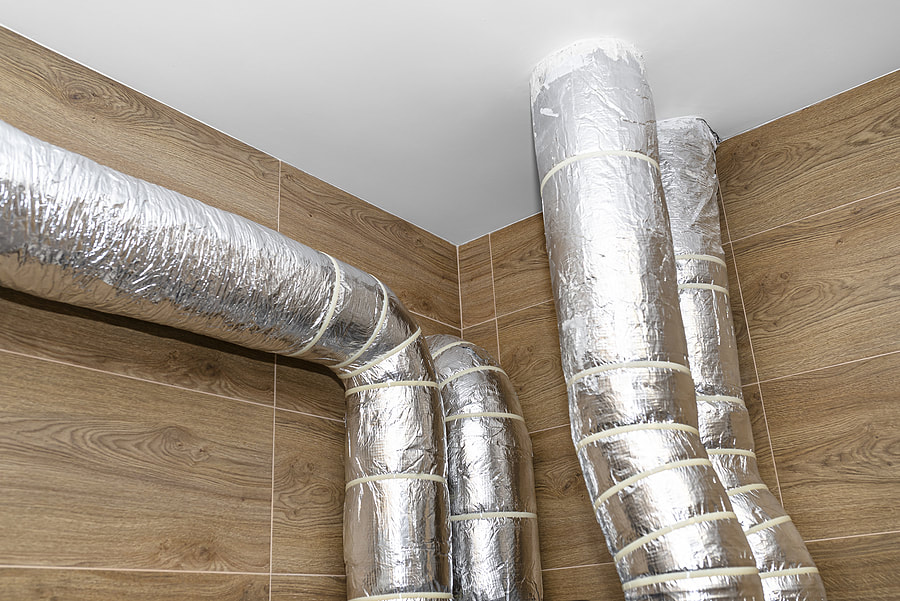 Heat recovery in Fairfield CT with visible insulated pipes and silver foil entering the ceiling by Fairfield Insulation.