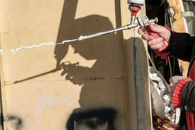 An employee of Fairfield Insulation uses an aerosol foam gun in Fairfield, CT.