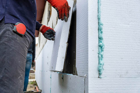 A worker from Fairfield Insulation installs styrofoam insulation sheets on the facade wall of a house in Fairfield, Connecticut.
