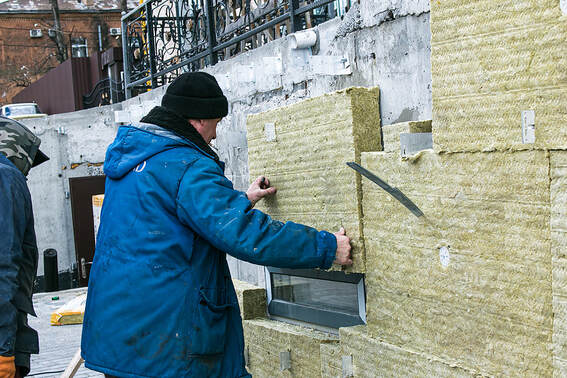 A man applies thermal insulation panels made of mineral wool in Fairfield, CT.