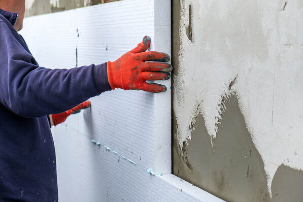 A Fairfield, CT, insulation contractor installs foam insulation panels on a house facade wall for thermal protection.